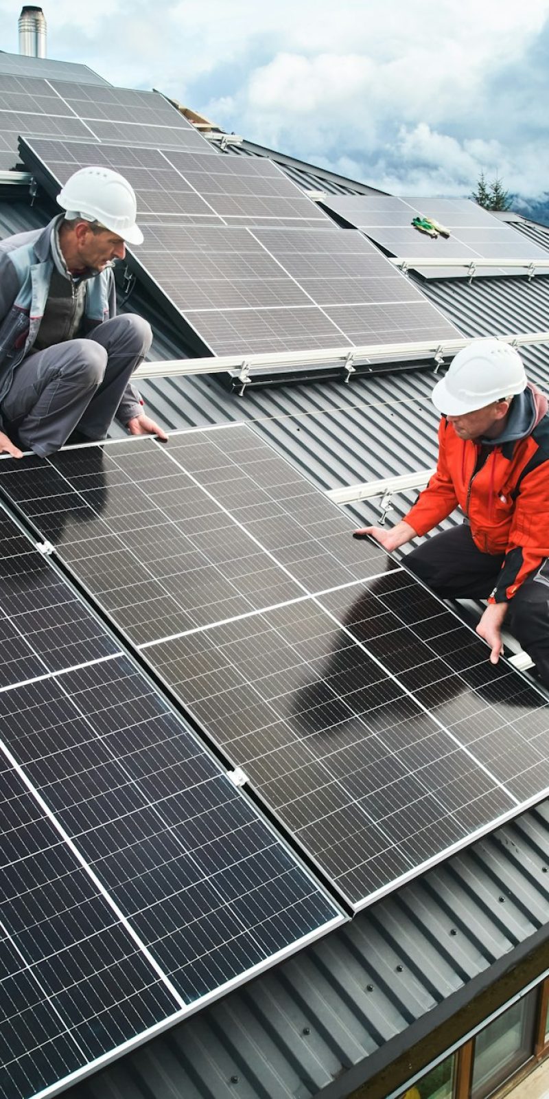 Men workers installing solar panels on roof of house.